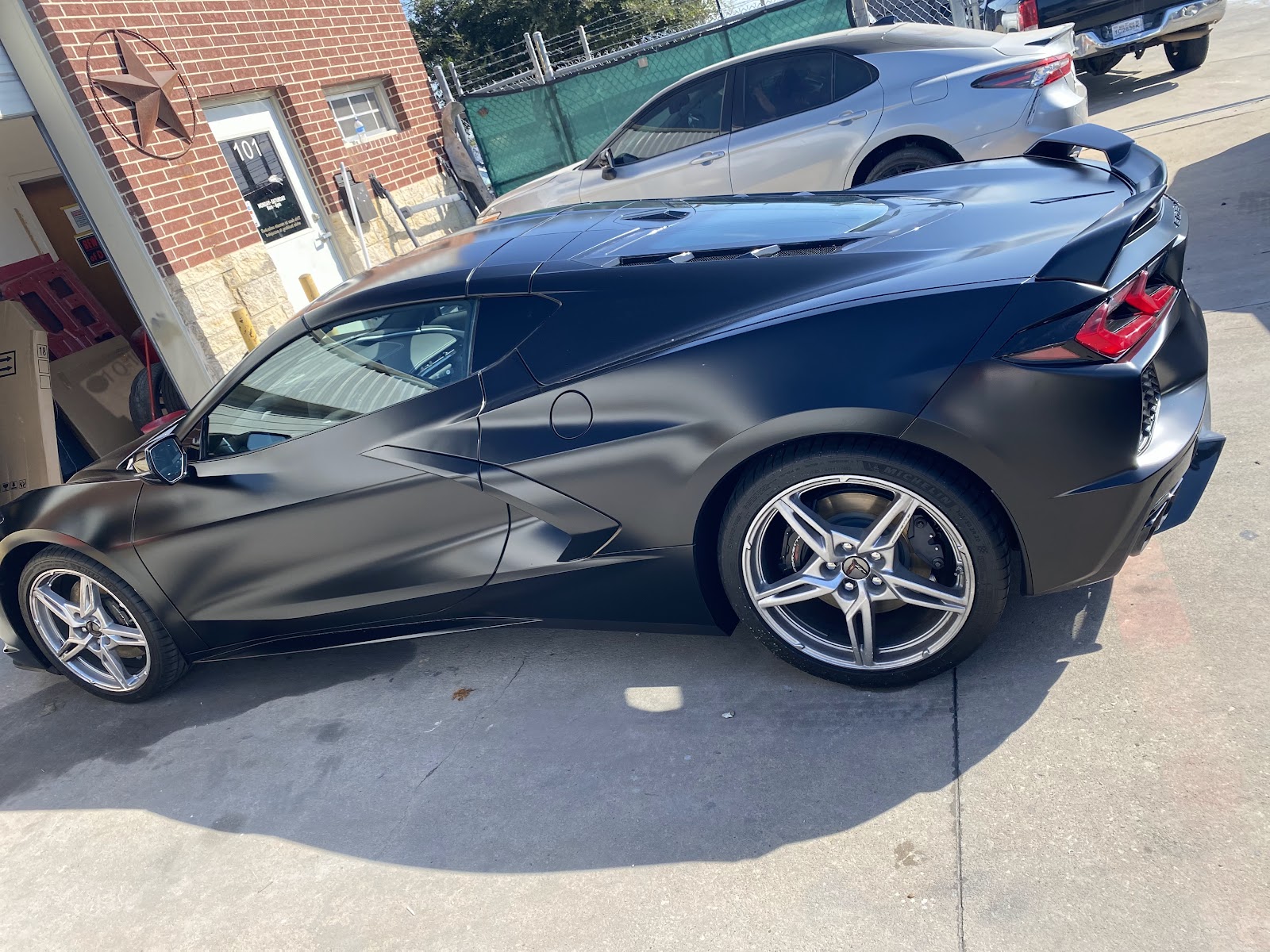 Side profile of a satin black Corvette C8 outside the 8SRT shop in Garland