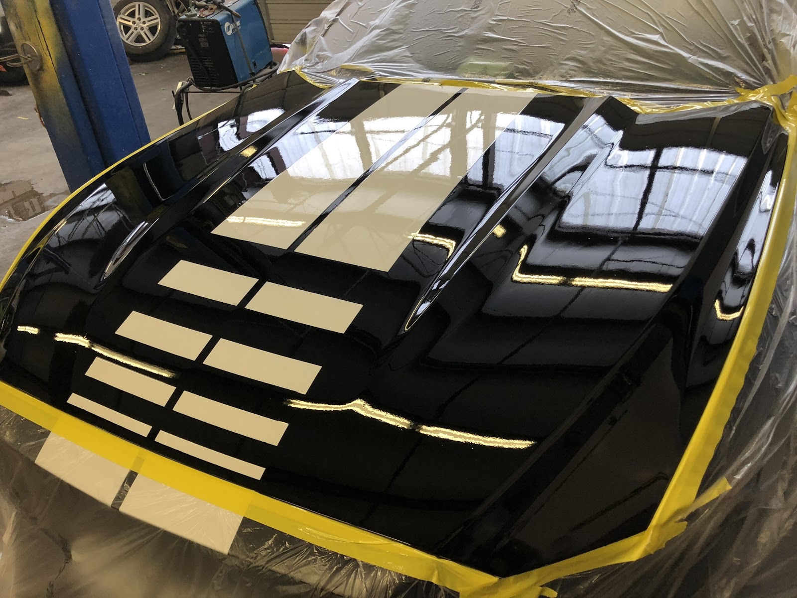 Glossy black hood with white racing stripes fresh out of paint at 8SRT Collision and Paint